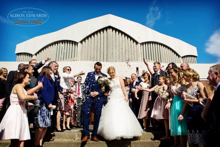 bride and groom having confetti thrown over them coming out of church
