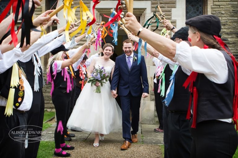 bride and groom walking under Morris Dancers at The Gilstrap Newark