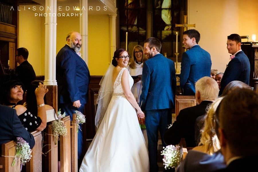 bride and groom laughing at alter st james church papplewick Nottingham captured by Nottingham wedding photographer Alison Edwards