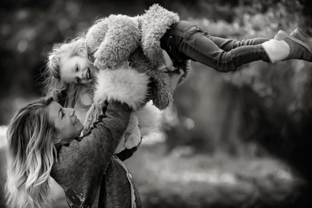 mum throwing daughter in air in park on mummy and me photoshoot