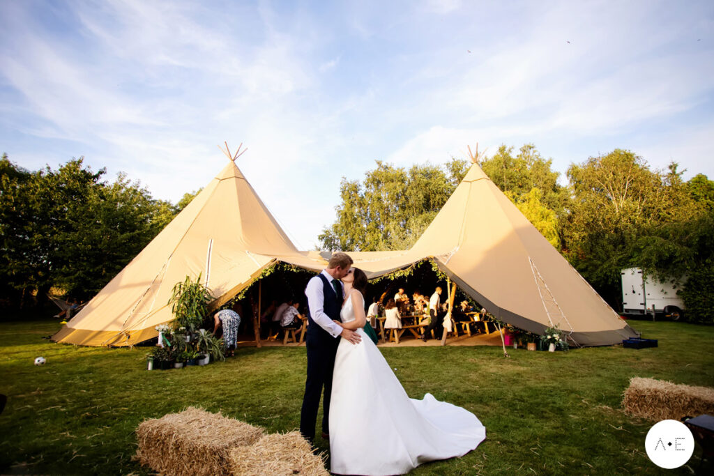 bride and groom kissing in front of tipis at lincolnshire wedding