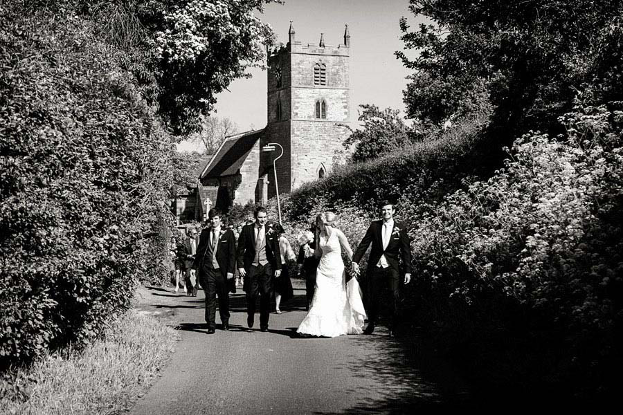 bride and groom walking from church on summers day captured by natural wedding photographer in Nottingham