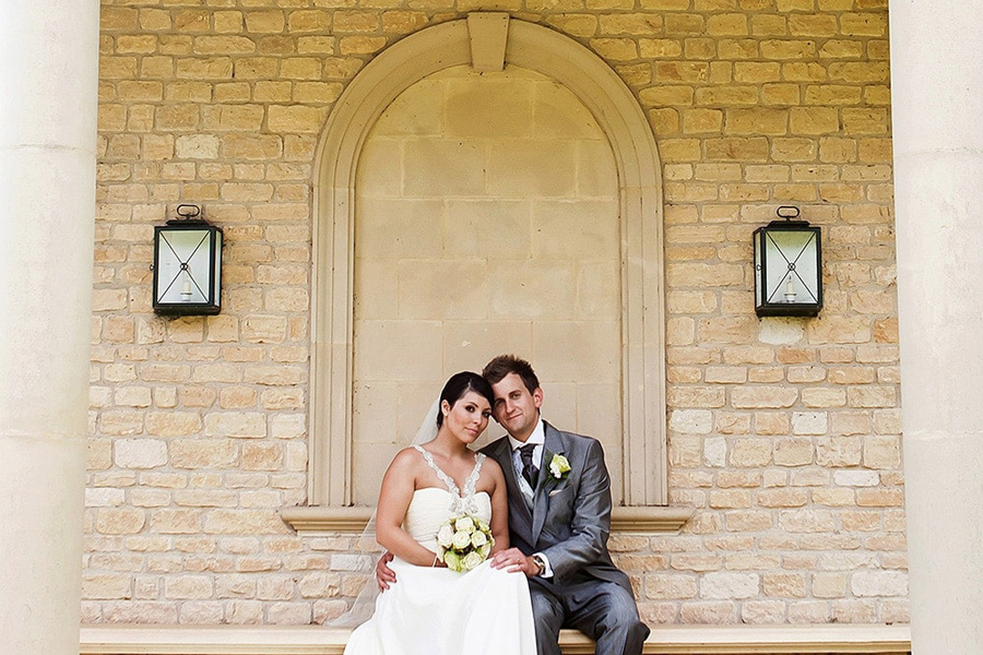 natural portrait of bride and groom on seat at Hambleton Hall