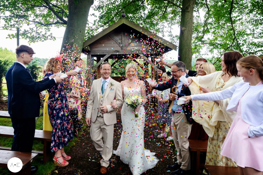 bride and groom walking down aisle outdoors confetti at morley Hayes Derbyshire captured by Alison Edwards Photography