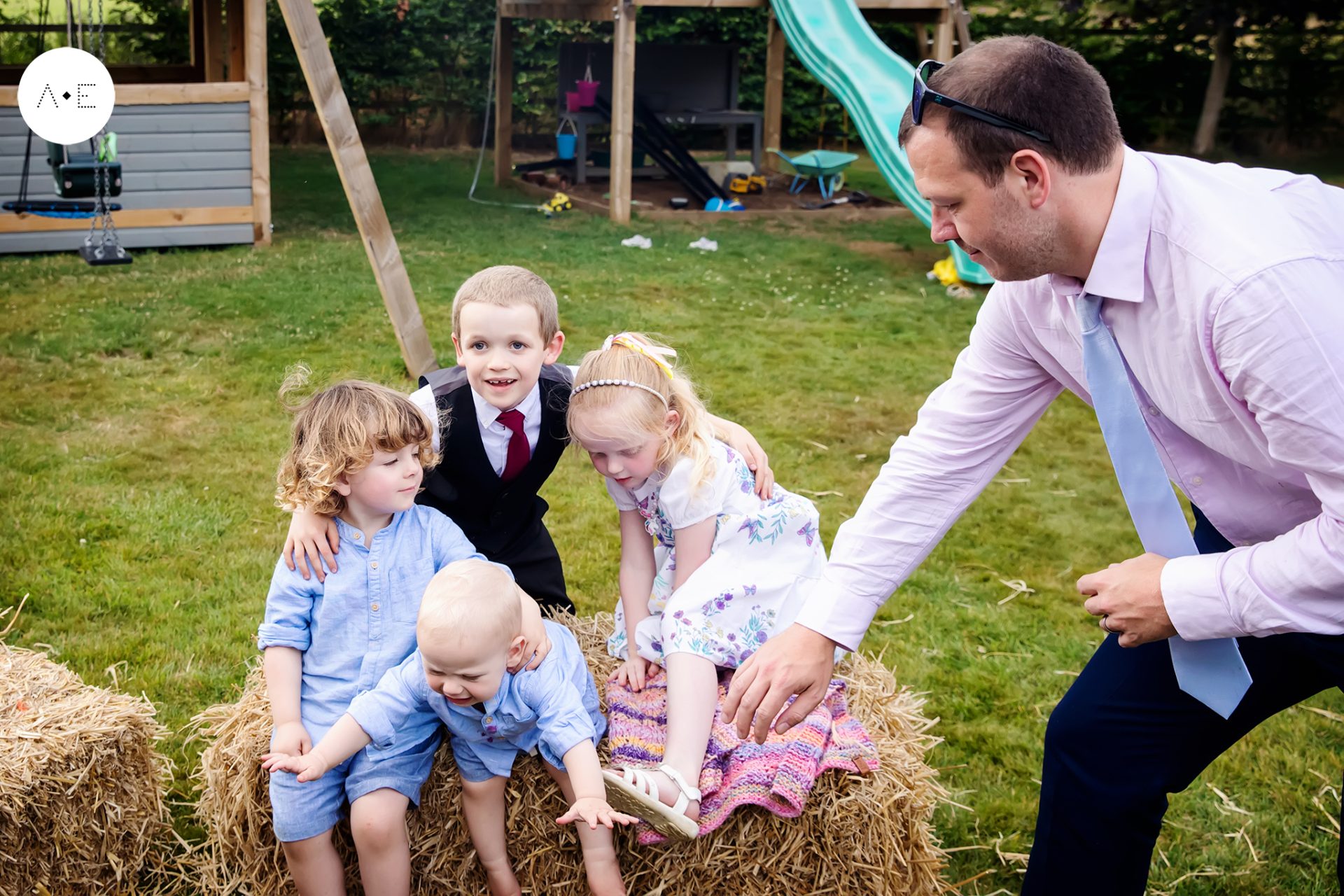 children on haystack in garden, young boy falling wedding captured documentary wedding photographer Alison Edwards