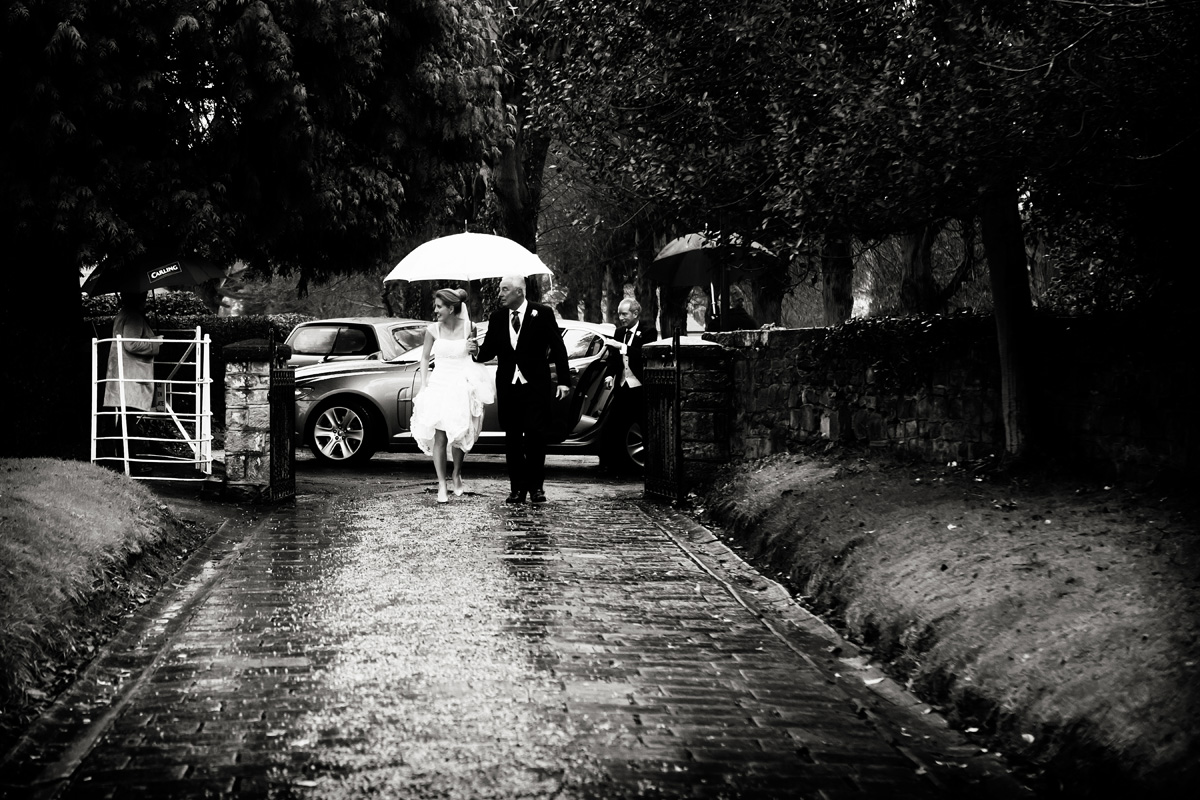 bride walking into church rainy day captured by twilight wedding photographer Alison Edwards Photography